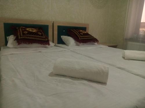 two beds with white sheets and a towel on them at Elita House Samarkand in Samarkand