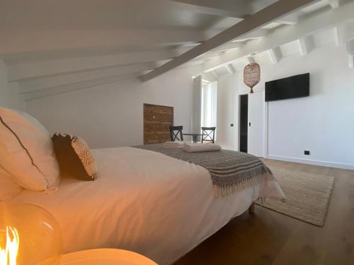 - une chambre avec un grand lit et une télévision dans l'établissement Grândola Suites - Suite Loft, à Grândola