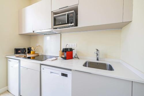 une cuisine blanche avec un évier et un micro-ondes dans l'établissement Quiet and luxurious studio - Cannes Center, à Cannes