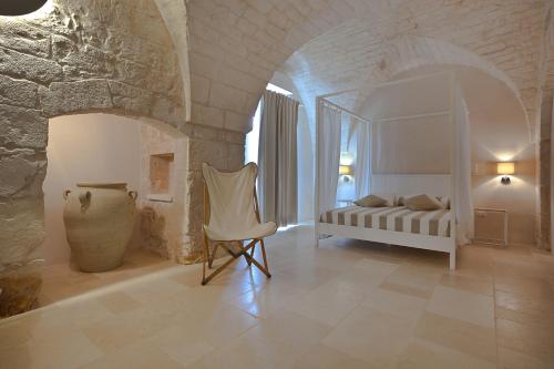 a bedroom with a bed and a chair in a room at Masserie Maresca in Ostuni