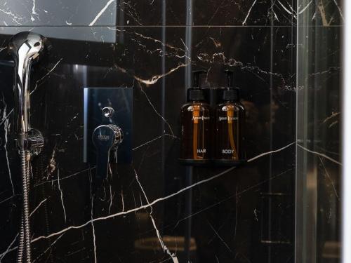 a black tiled bathroom with a shower with a blow dryer at Daedalus in Athens