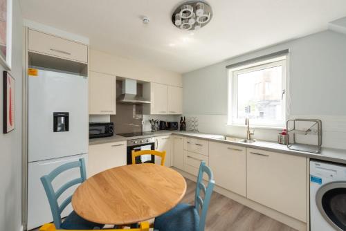 uma cozinha com uma mesa de madeira e uma cozinha com armários brancos em Ground Floor 2 Bed Flat Slateford em Edinburgo