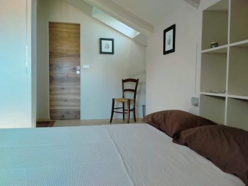 a bedroom with a bed and a chair and a door at B&B San Gregorio in Cherasco