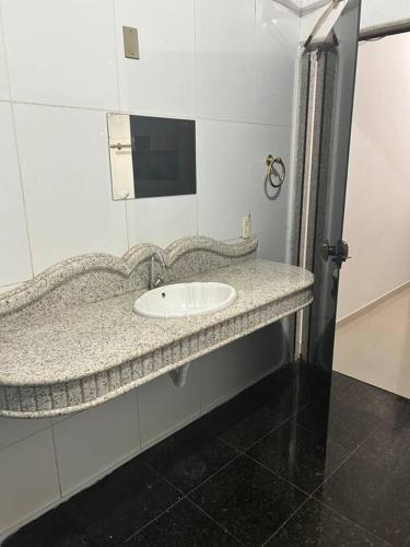 a bathroom with a sink and a mirror at Apartamento completo ao lado praça dos girassóis in Palmas