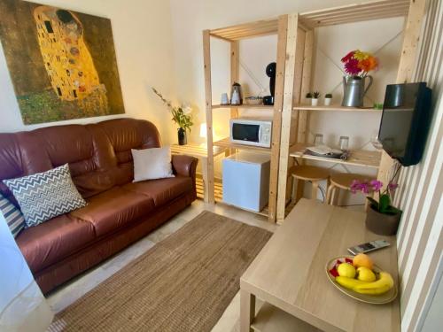 uma sala de estar com um sofá e uma mesa com uma taça de fruta em Plaza de San Francisco em Málaga