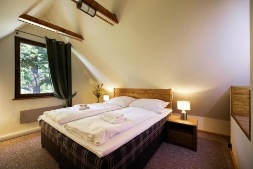 Schlafzimmer mit einem Bett mit weißer Bettwäsche und einem Fenster in der Unterkunft Chalet Green Park in Stará Lesná