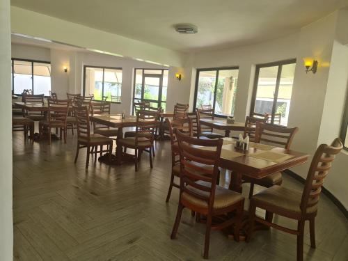 ein Restaurant mit Holztischen, Stühlen und Fenstern in der Unterkunft Ol Muteita Lodge in Nakuru