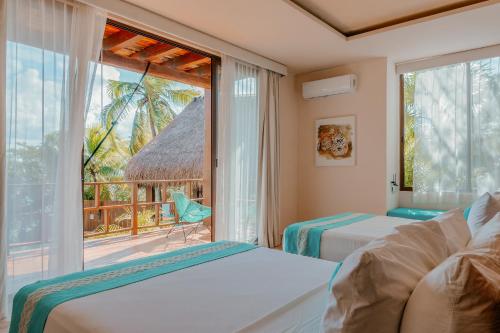 a bedroom with two beds and a large window at Khaban Bacalar Hotel Boutique in Bacalar