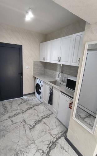 eine Küche mit weißen Schränken, einer Waschmaschine und einer Spüle in der Unterkunft Студио Ава 2 in Sliven