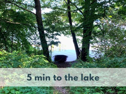 a black bear sitting in the woods with the words min to the lake at Ferienhaus Marianna am See mit gratis Sauna, Ruderboot & WLAN in Krzywonoga