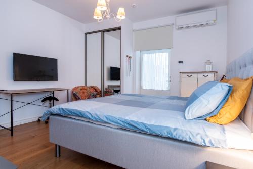 a bedroom with a bed with blue sheets and a television at Sunny Terrace Flat with AC Free WiFi Self Check In in Pärnu