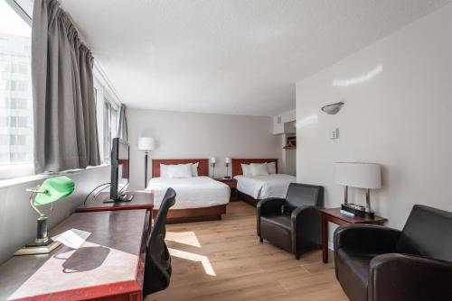 モントリオールにあるホテル レ スイーツ ラベルのベッド2台とデスクが備わるホテルルームです。