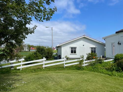 a white fence in front of a white house at Charming coastal house with an ocean view in Garten