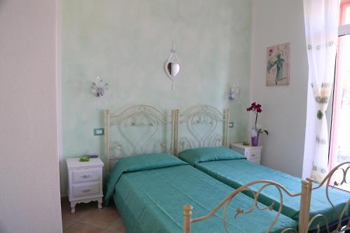 een slaapkamer met een bed met een groen dekbed bij B&B Le Rose in Olbia