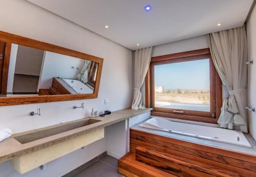 a bathroom with a tub and a large mirror at Maale Caraúbas in Camocim