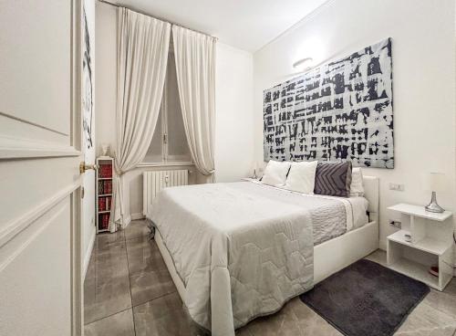 una camera bianca con un letto e una foto appesa al muro di Casa Alberto da Giussano, elegante bilocale in centro con balcone sul parco a Milano