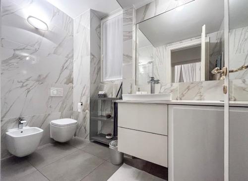 biała łazienka z toaletą i umywalką w obiekcie Casa Alberto da Giussano, elegante bilocale in centro con balcone sul parco w Mediolanie