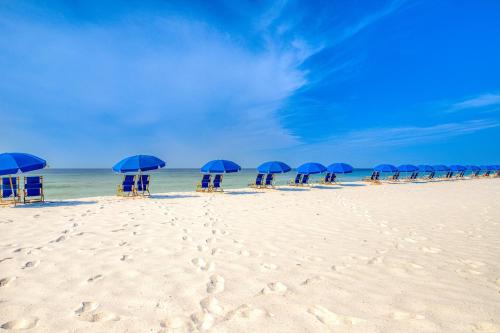 a group of blue umbrellas and chairs on a beach at Lei Lani Village 103 in Orange Beach