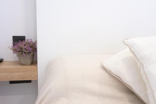 een wit bed met een kussen en een vaas met bloemen bij Apartamentos Brillante 156 in Córdoba