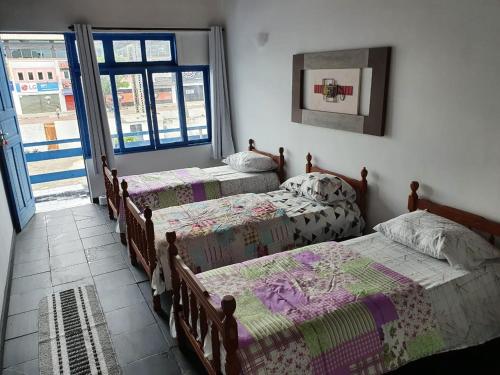 a bedroom with three beds and a window at Pousada do Goiano in Cabo Frio