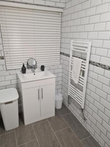 Baño blanco con lavabo y espejo en North Parade Holiday Apartment 35 Sea View Road Skegness PE25 1BS en Skegness