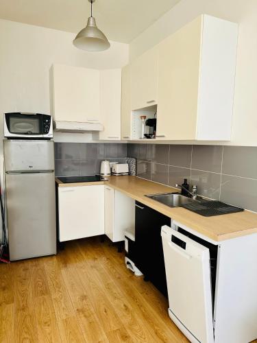 une cuisine avec des armoires blanches et un plancher en bois dans l'établissement Maison 50 m2, à 5 minutes de Paris et idéal pour Disney, à Montreuil