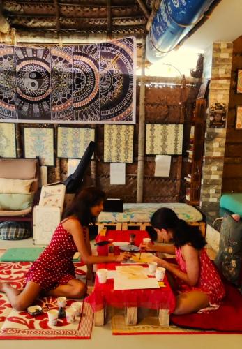 two women sitting at a table in a room at Jambavan Arts Sanctuary in Varkala