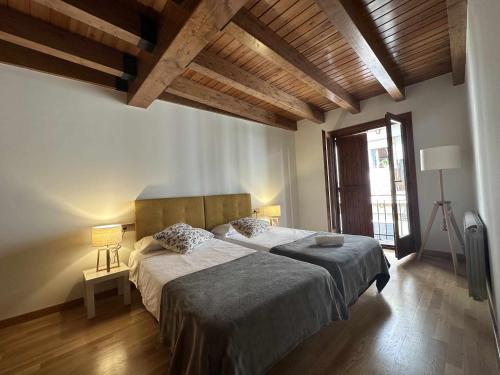 - une chambre avec un grand lit dans une pièce dotée de plafonds en bois dans l'établissement Casa Baronia La Cerdanya, à Puigcerdà