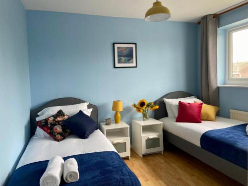 ケンブリッジにある3 Bedroom House Garden Free Parking 15 min to centre 5 min to motorwayの青い壁の部屋にベッドが2つある