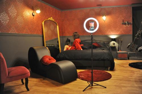 a woman sitting on a bed in a room with a mirror at L'Un Des Sens in Châtel-Guyon