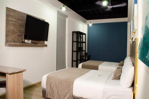 a bedroom with two beds and a tv on the wall at Hotel StayHome in Ensenada