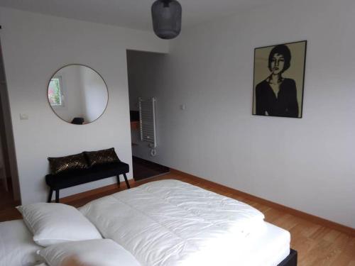 - un lit blanc dans une chambre avec un miroir dans l'établissement Détente à Granville, à Yquelon