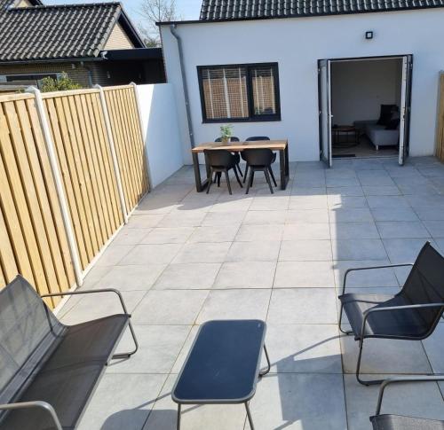 a patio with chairs and a table and a fence at Calm Down Near The Sea in Vlissingen