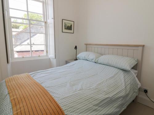 a bed in a bedroom with a window and a bedspread at 6 Kirkstyle in Biggar
