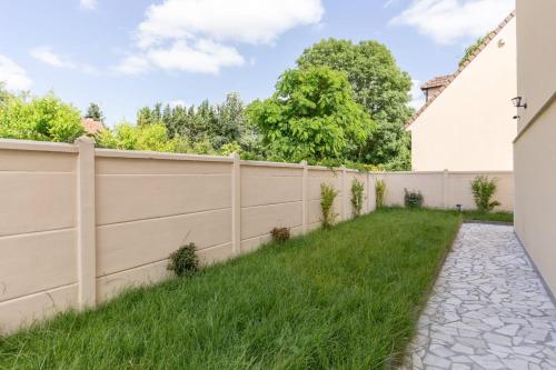 une clôture dans une cour avec de l'herbe verte dans l'établissement Maison élégante et spacieuse, à Écouen