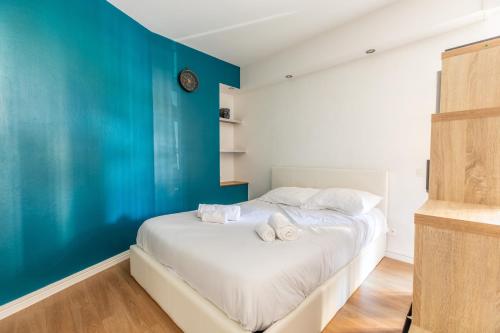 een slaapkamer met een bed met een blauwe muur bij Astridôme in Châtel-Guyon