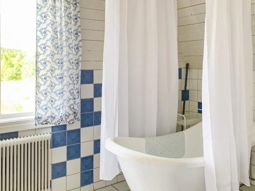 La salle de bains est pourvue d'une baignoire blanche et d'une fenêtre. dans l'établissement Holiday home VETLANDA, à Vetlanda