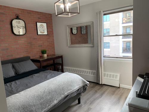 a bedroom with a brick wall and a bed and a clock at Brooklyn Studios By The Beach in Brooklyn