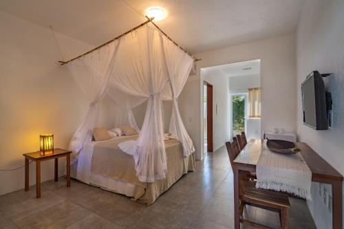 Schlafzimmer mit einem Bett mit Moskitonetz in der Unterkunft Charm Bahia Suites in Arraial d'Ajuda