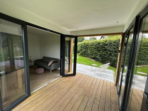 une véranda avec un canapé sur une terrasse en bois dans l'établissement De Texelaar, à Elspeet