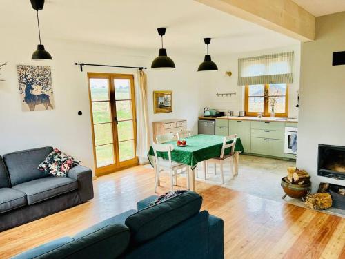 a living room with a green table and a kitchen at Świętokrzyskie Stodoła Kasztanowa Aleja Radkowice in Radkowice