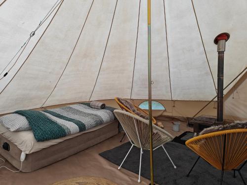 ein Bett und Stühle in einem Zimmer mit Segel in der Unterkunft Au Pied Du Trieu, the glamping experience in Labroye