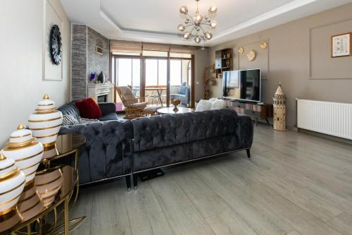 un soggiorno con divano nero e TV di VIP VILLA IN BEYLIK DUZU WITH SEA VIEW a Beylikdüzü