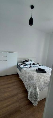 a white bedroom with a bed and a dresser at Apartament z tarasem Kutno in Kutno