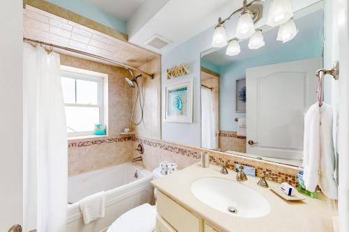a bathroom with a tub and a sink and a mirror at Tybee T's Chu Beach Condo in Tybee Island