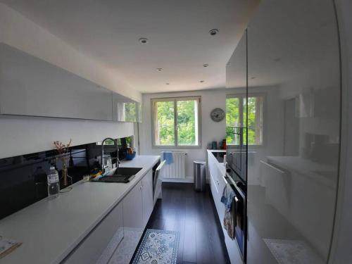 a white kitchen with a sink and a stove at Appartement Le Havre, 50 m de la plage in Sainte-Adresse