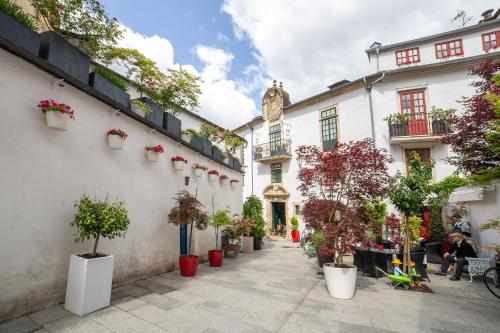 a courtyard with potted plants and a clock tower at Hotel Monumento Pazo de Orbán in Lugo