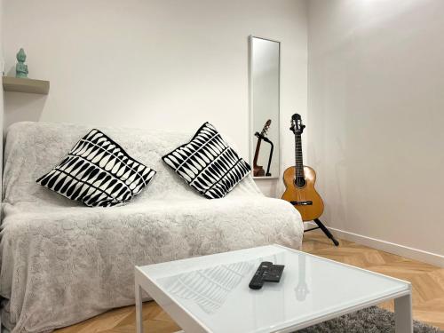 salon z kanapą z 2 poduszkami i gitarą w obiekcie Le Coeur De Fontainebleau 1-Bedroom Retreat w mieście Fontainebleau