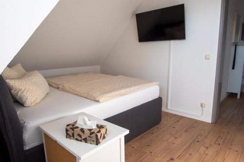 a small bedroom with a bed and a tv on the wall at NB Katharinenviertel Zwei Zimmer Wohnung in Neubrandenburg