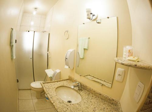 ein Badezimmer mit einem Waschbecken, einem WC und einem Spiegel in der Unterkunft GOLDMEN HOTEL MARINGÁ in Maringá